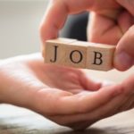 Hand holding wooden blocks spelling "JOB," symbolizing professional opportunities and hiring in the plumbing industry.